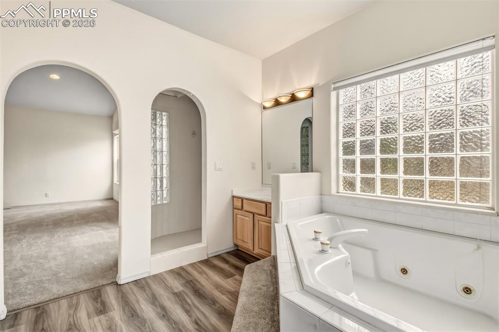 Image 23 of 35: Full bath with vanity, a tub with jets, light wood-style flooring, recessed