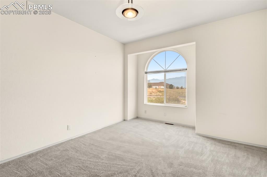 Image 26 of 35: Empty room with light colored carpet and a mountain view