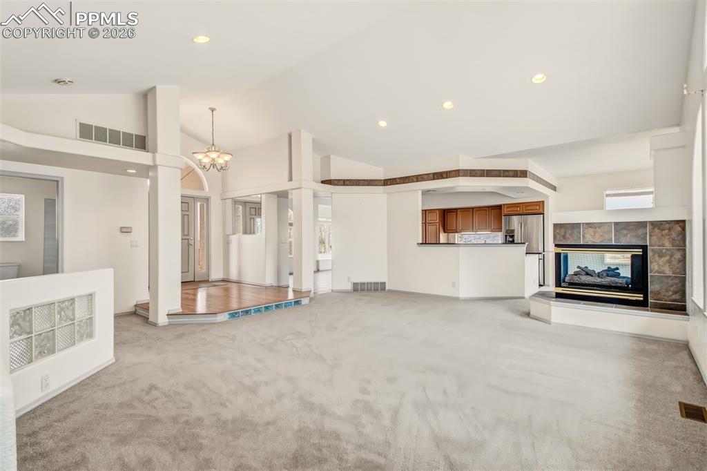 Image 9 of 35: Unfurnished living room featuring lofted ceiling, light colored carpet, a t