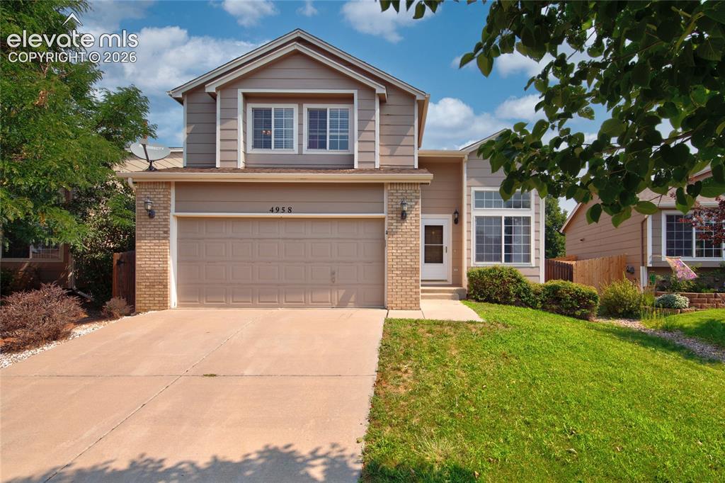 Caption: Two-story residence featuring a two-car attached garage, a concrete driveway, and front brick accent