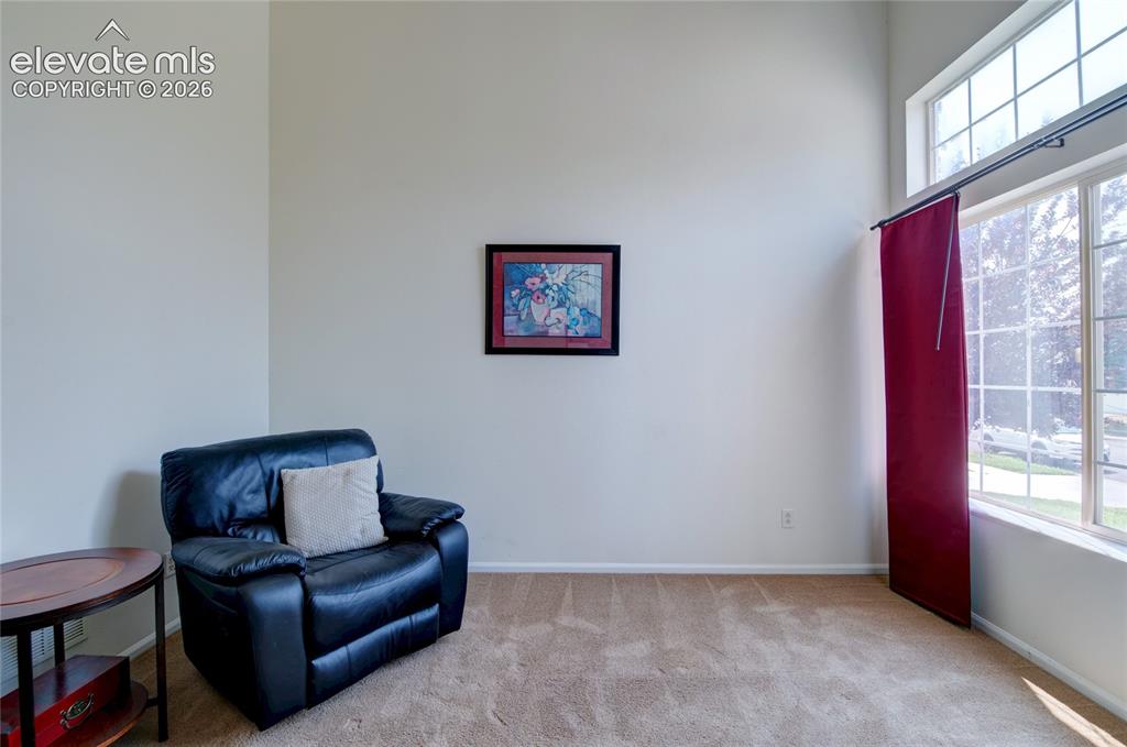 Image 11 of 34: Carpeted interior space featuring a double-height ceiling, large bay window