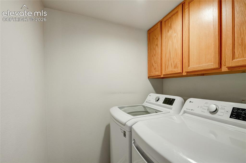 Image 14 of 34: Dedicated laundry space featuring upper wood cabinetry