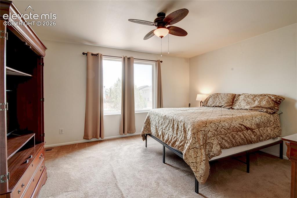 Image 15 of 34: Carpeted room featuring a ceiling fan with integrated lighting, dual window