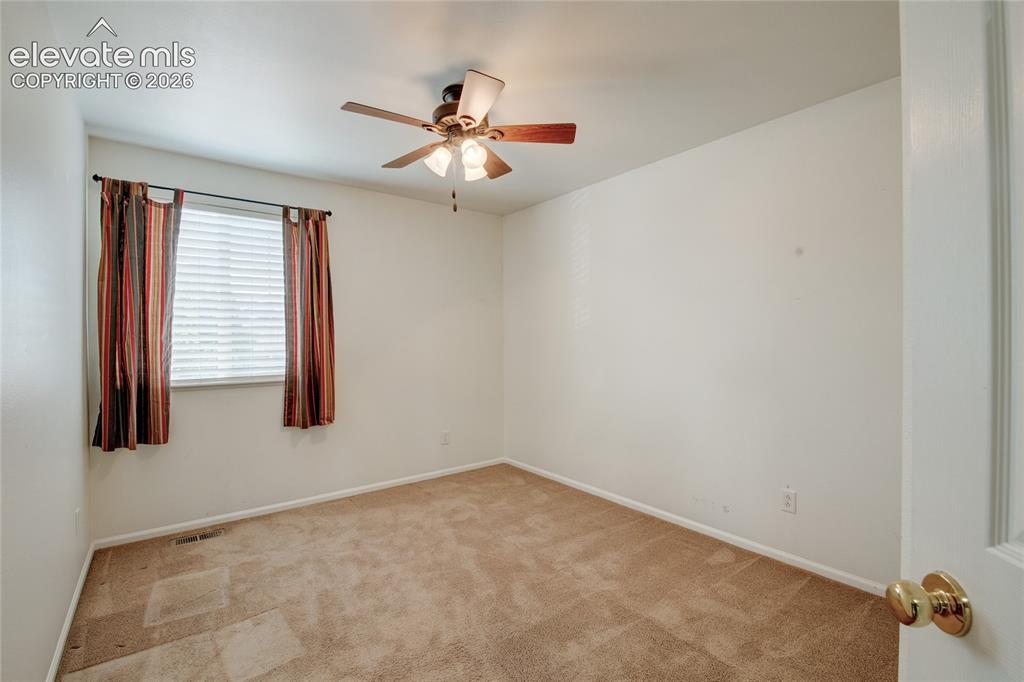 Image 21 of 34: Neutral-toned room with a ceiling fan light fixture, beige wall-to-wall car