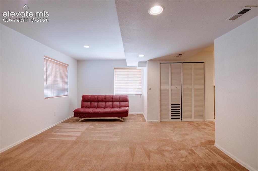 Image 27 of 34: Carpeted room featuring white walls, two windows with horizontal blinds, re