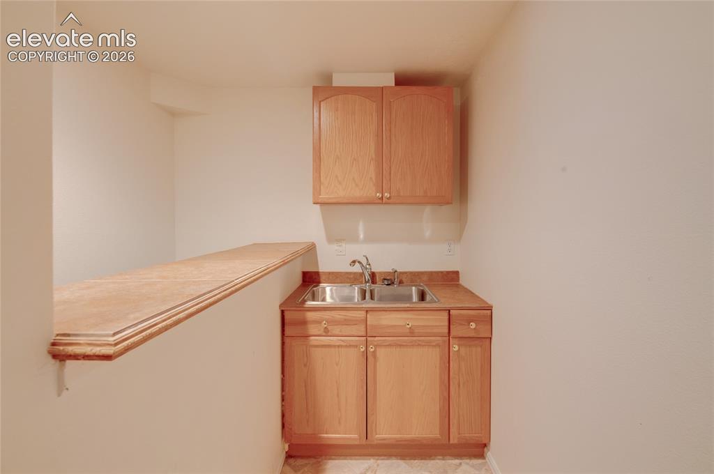 Image 29 of 34: Kitchenette featuring light wood-finish cabinetry, a dual basin stainless s