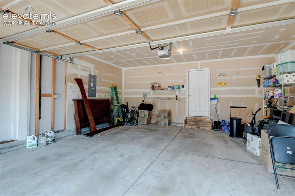 Image 30 of 34: Concrete flooring garage with an overhead automatic door system