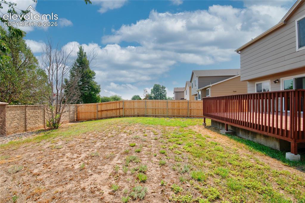 Image 34 of 34: Expansive outdoor area featuring a wooden privacy fence, a retaining wall, 