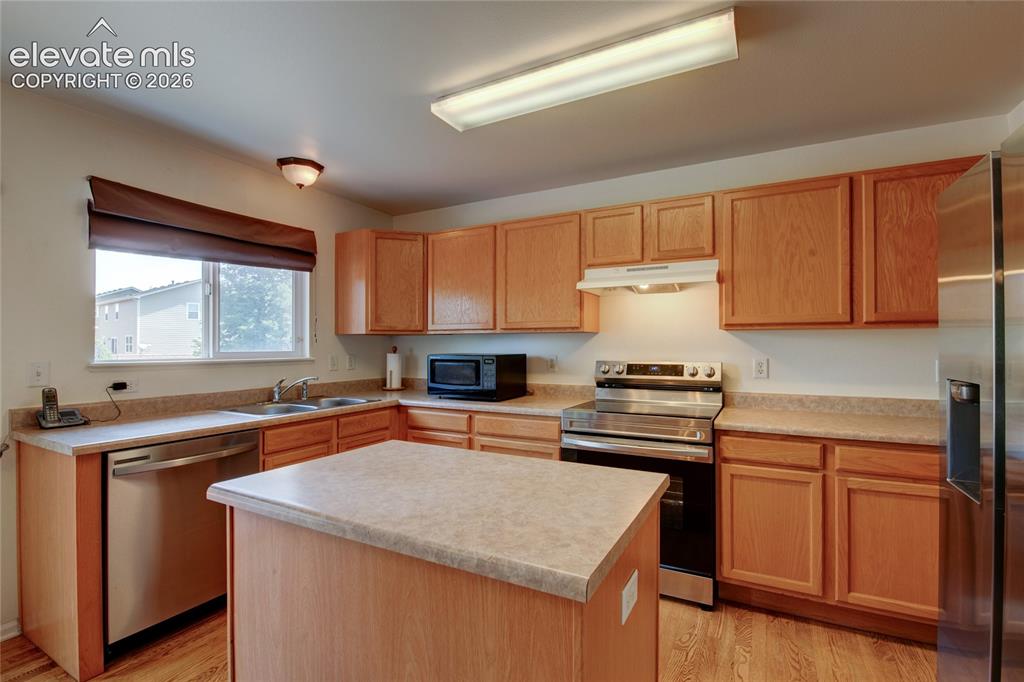 Image 4 of 34: Kitchen featuring a center island, light wood cabinetry, light-toned counte