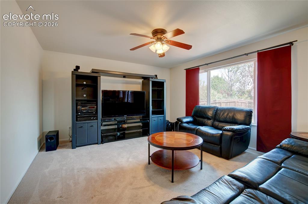 Image 8 of 34: Carpeted living area featuring a ceiling fan with integrated lighting, a la