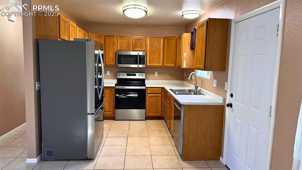 Image 10 of 34: Kitchen with appliances with stainless steel finishes, light countertops, l