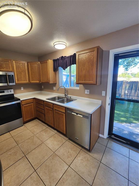 Image 11 of 34: Kitchen featuring brown cabinets, stove, light countertops, stainless steel