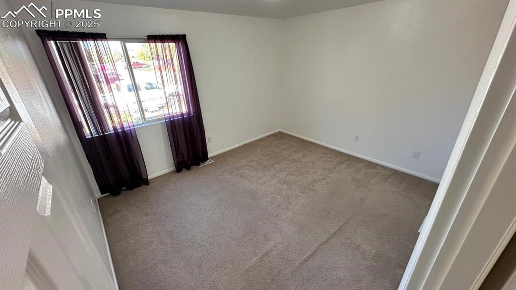 Image 25 of 34: Spare room with carpet and baseboards. un-staged