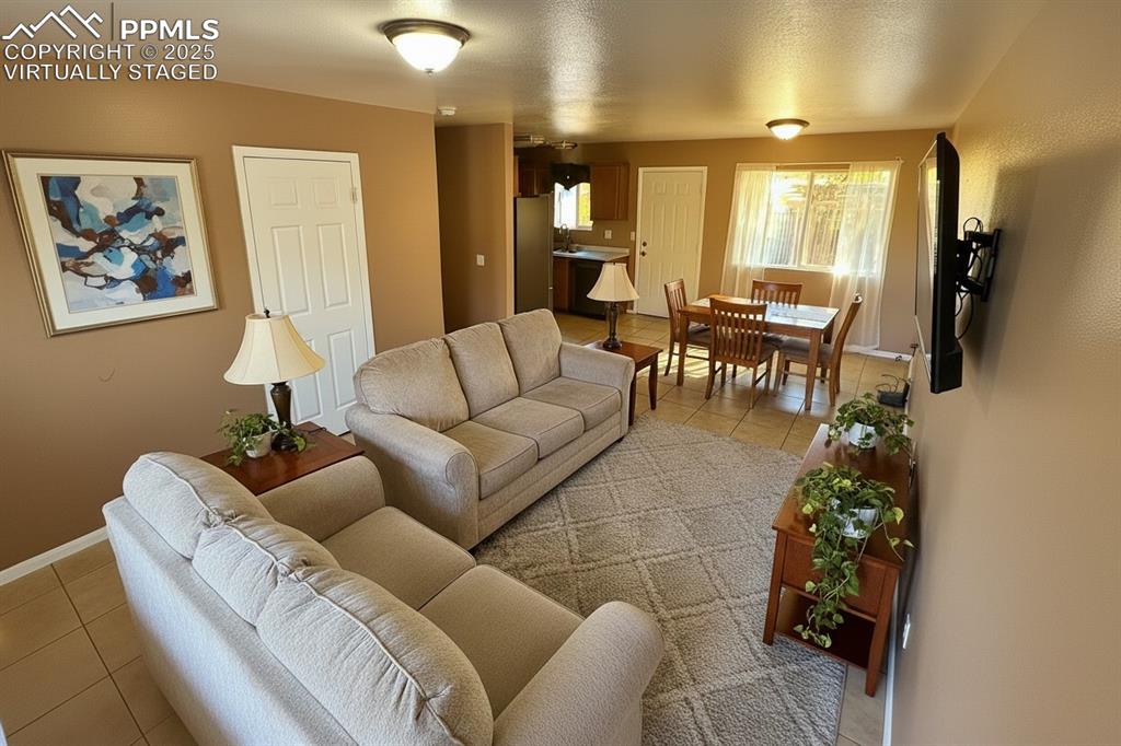 Image 7 of 34: Living area featuring light tile patterned floors and a textured ceiling.