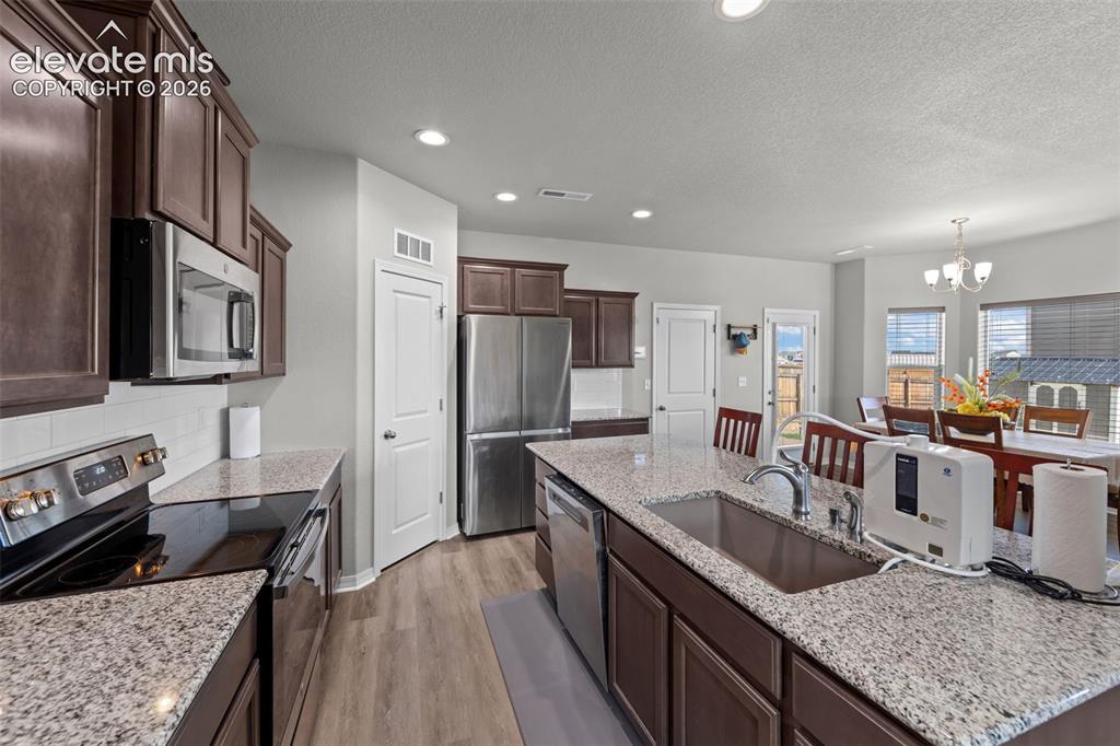 Image 12 of 41: Kitchen featuring dark wood-finish cabinetry, stainless steel appliances, g