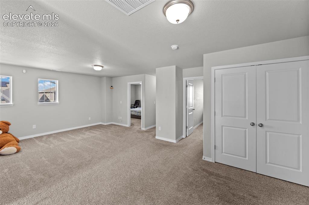 Image 13 of 41: Expansive carpeted area with multiple windows, recessed lighting, and a dou