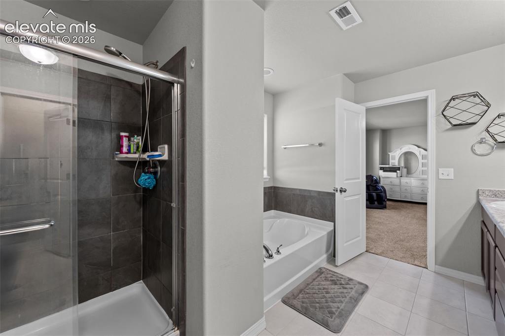 Image 18 of 41: Shower with sliding glass enclosure and dark tile surround
