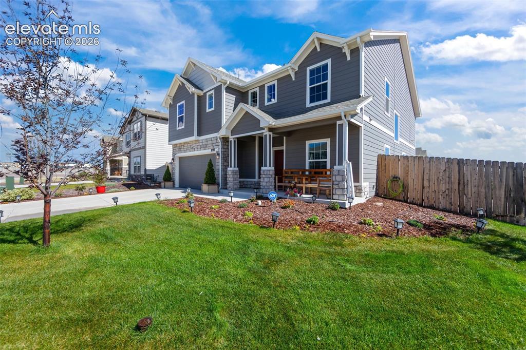 Image 2 of 41: Two-story residence featuring grey siding, stone accents, and a covered fro