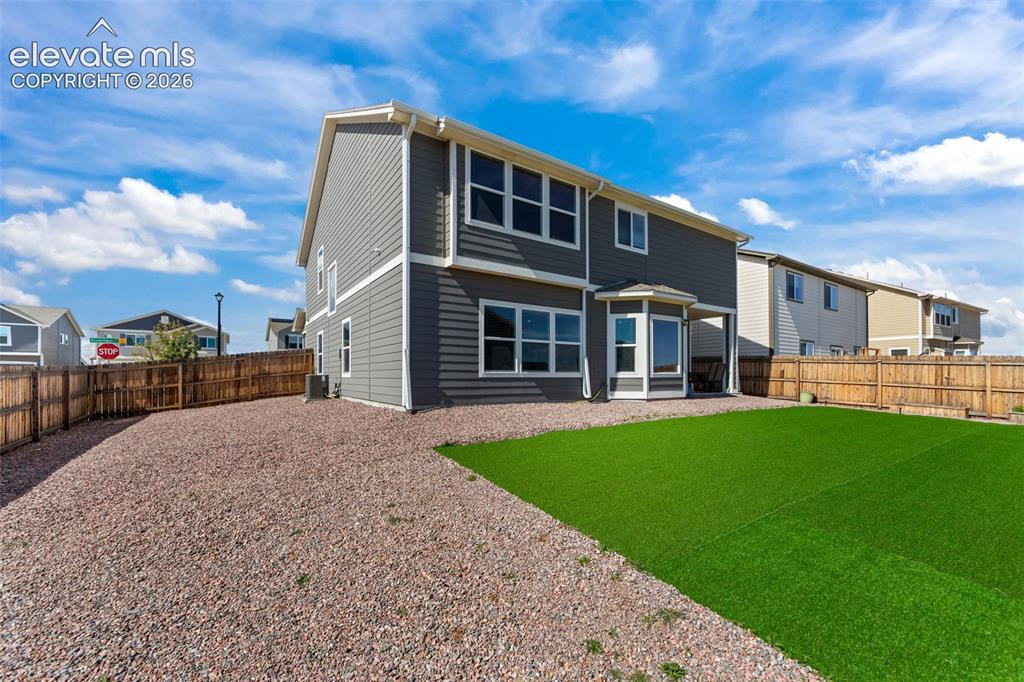 Image 29 of 41: Two-story exterior with gray siding, white trim, and a fenced backyard feat