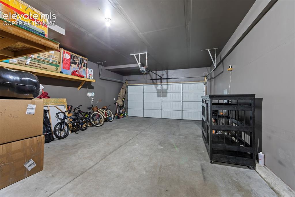 Image 30 of 41: Concrete flooring, overhead lighting, and a white paneled garage door