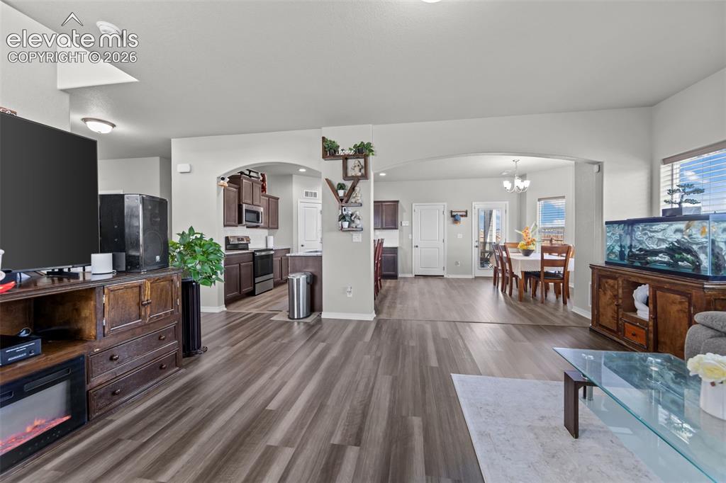Image 8 of 41: Spacious living area with wood-finish flooring, arched doorways, an open-co