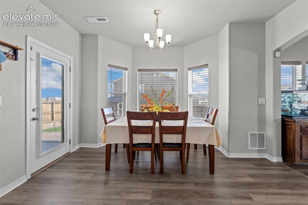 Image 9 of 41: Dining area with wood-finish flooring and a contemporary chandelier