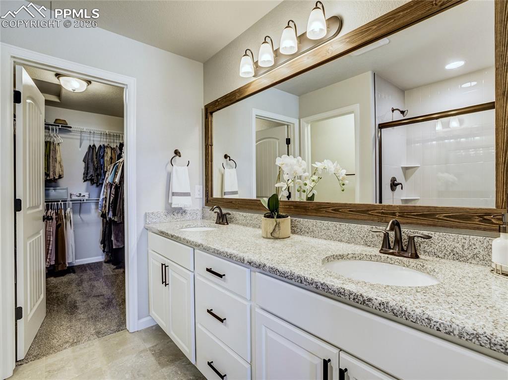 Image 10 of 45: The primary bath showcases granite countertops, a framed mirror, spacious s