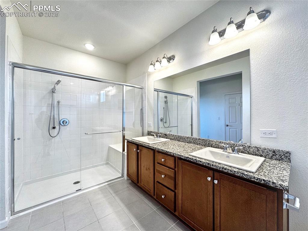 Image 21 of 29: Primary Bathroom with walk in shower, double sinks and stone vanity