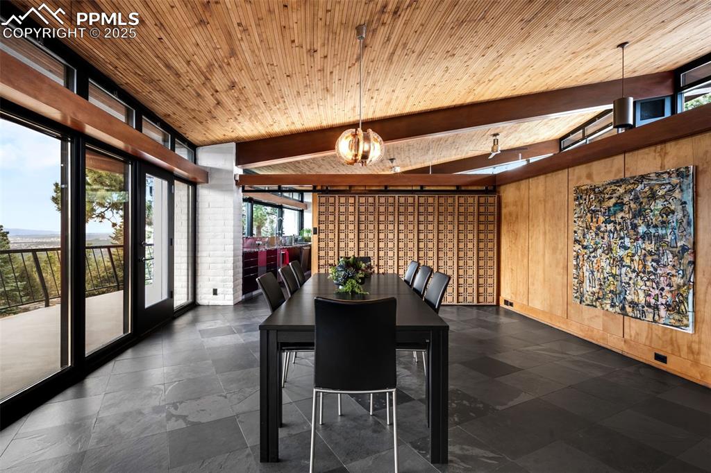Image 13 of 39: Dining space with wood walls and a wooden ceiling with exposed beams