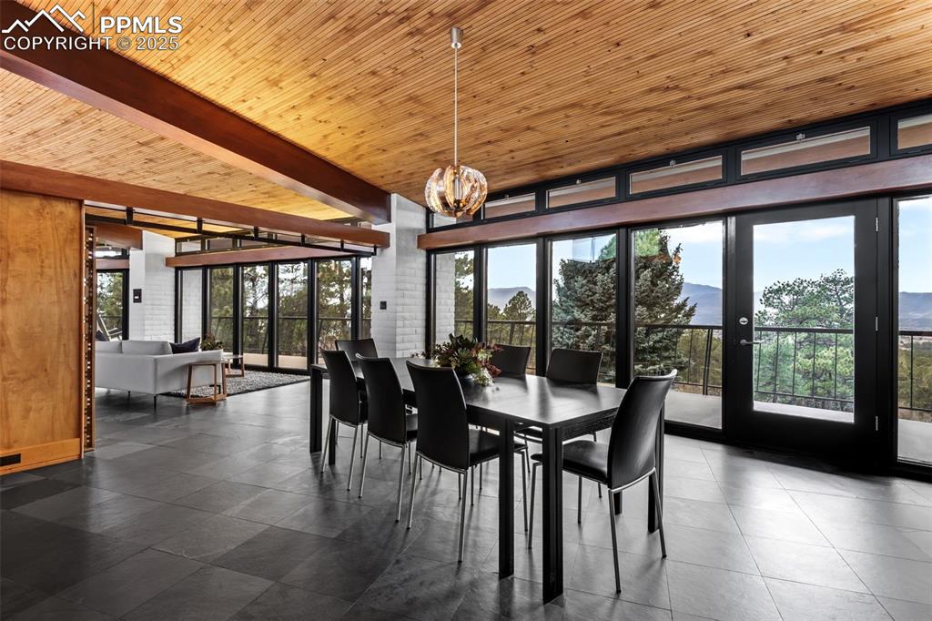 Image 14 of 39: Dining space with a mountain view, a wooden ceiling with exposed beams, exp