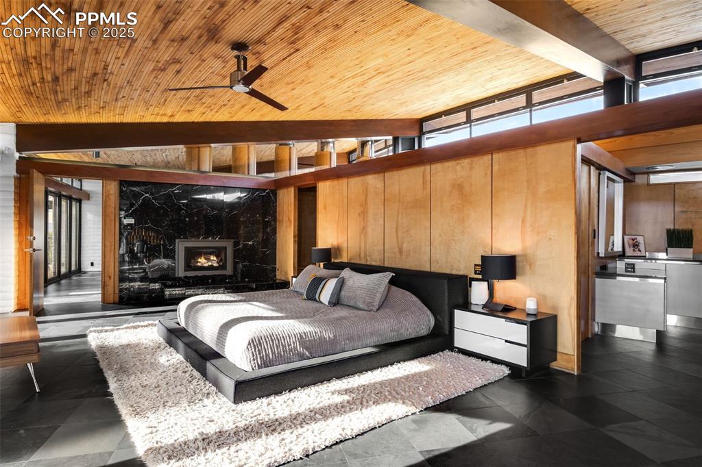 Image 15 of 39: Bedroom featuring wood walls and a wood ceiling with exposed beams