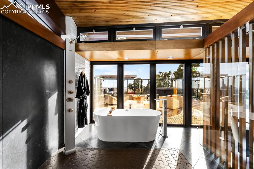 Image 18 of 39: Bathroom featuring plenty of natural light, a freestanding tub, wooden ceil