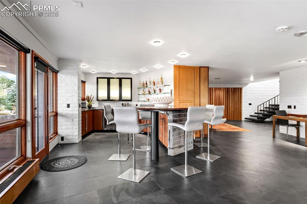 Image 22 of 39: Dining space featuring stairs and a bar