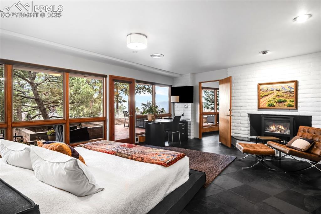 Image 25 of 39: Bedroom featuring a glass covered fireplace and access to exterior