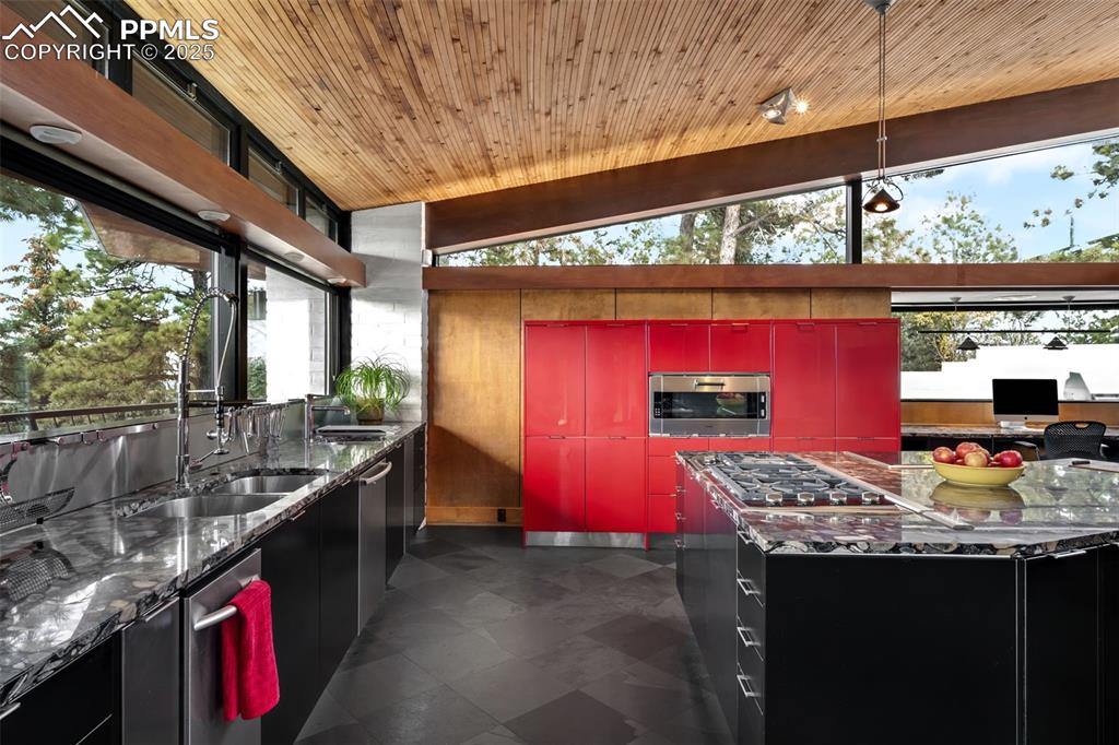Image 9 of 39: Kitchen with red cabinets, dark stone counters, modern cabinets, appliances