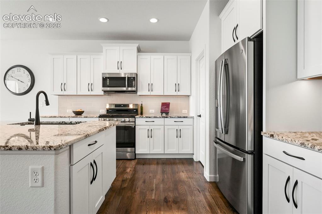 Image 15 of 38: Kitchen with stainless steel appliances, dark wood-style flooring, tasteful