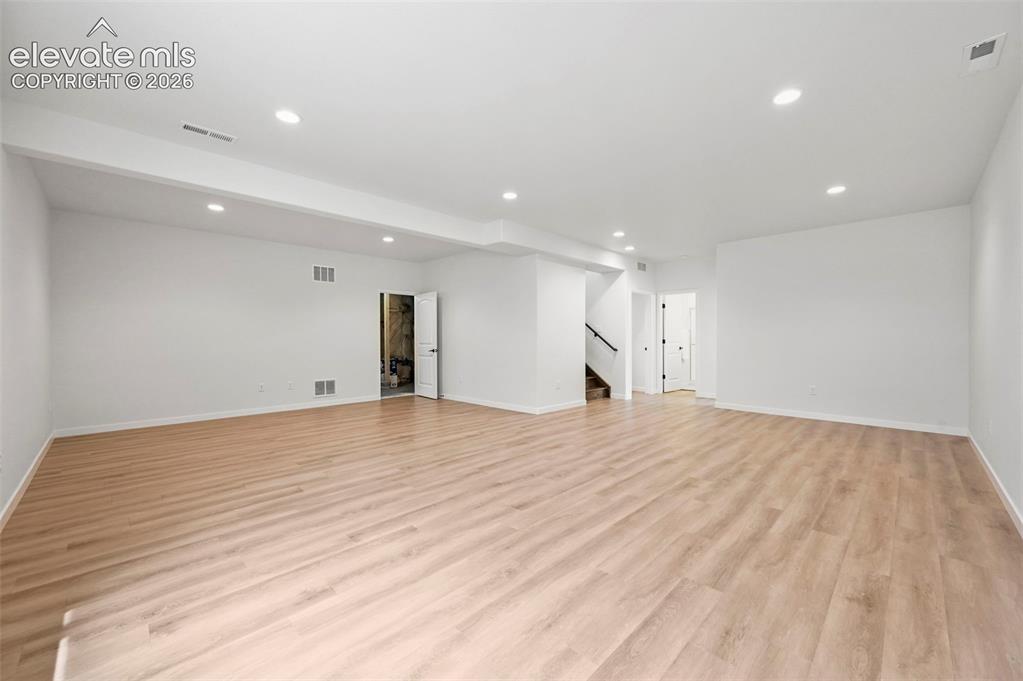 Image 25 of 38: Unfurnished living room with stairs, recessed lighting, and light wood fini