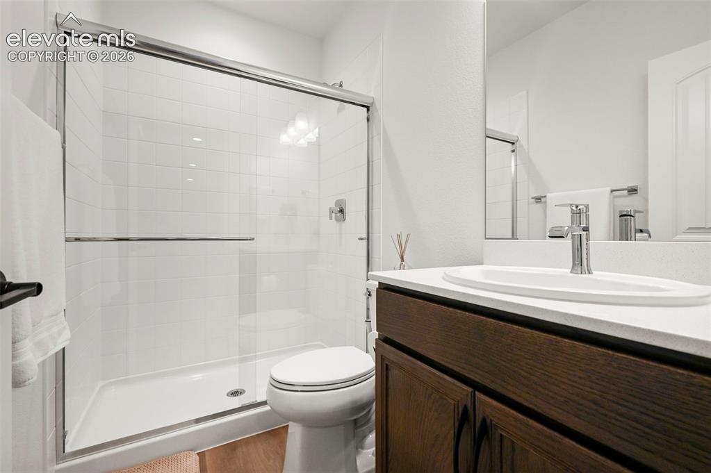 Image 28 of 38: Full bath with a shower stall, vanity, and wood finished floors