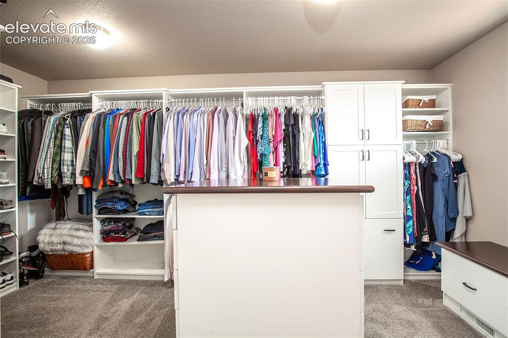 Image 28 of 45: Enormous walk-in closet featuring custom built-ins from the Closet Factory