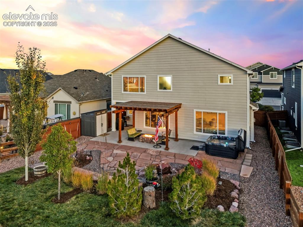 Image 34 of 45: The stunning backyard offers a flagstone patio, built-in gas firepit, pergo