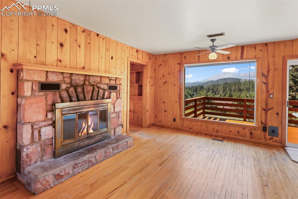 Image 10 of 35: Unfurnished living room featuring wood-type flooring, wood walls, a mountai