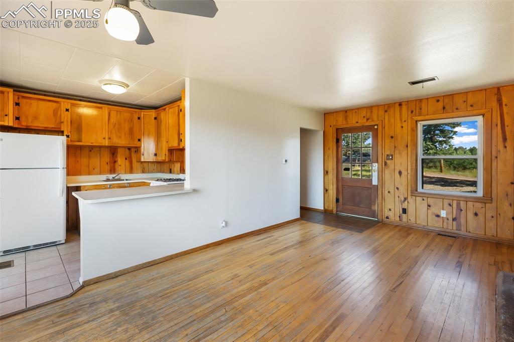Image 15 of 35: Kitchen with freestanding refrigerator, light wood-style floors, light coun