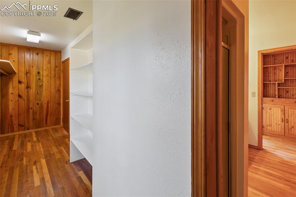 Image 23 of 35: Corridor with light wood finished floors and wooden walls