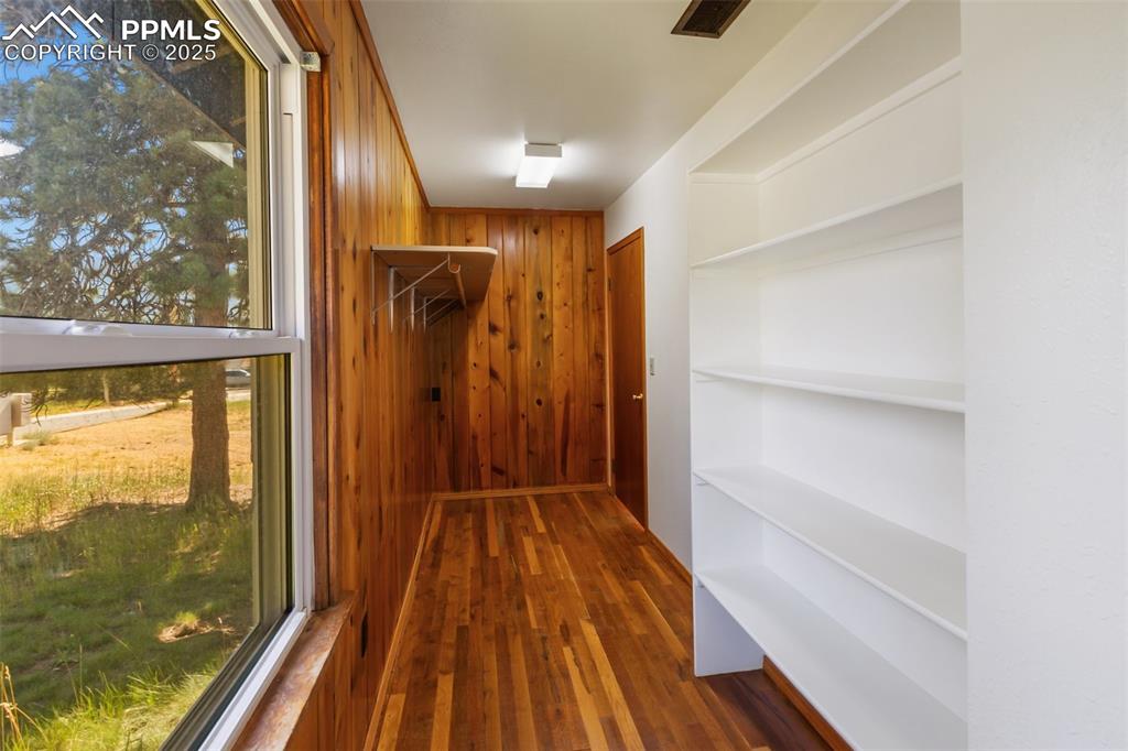 Image 24 of 35: Walk in closet with wood finished floors