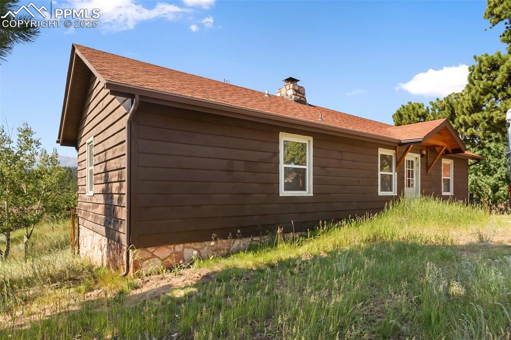 Image 31 of 35: View of property exterior featuring a chimney and roof with shingles