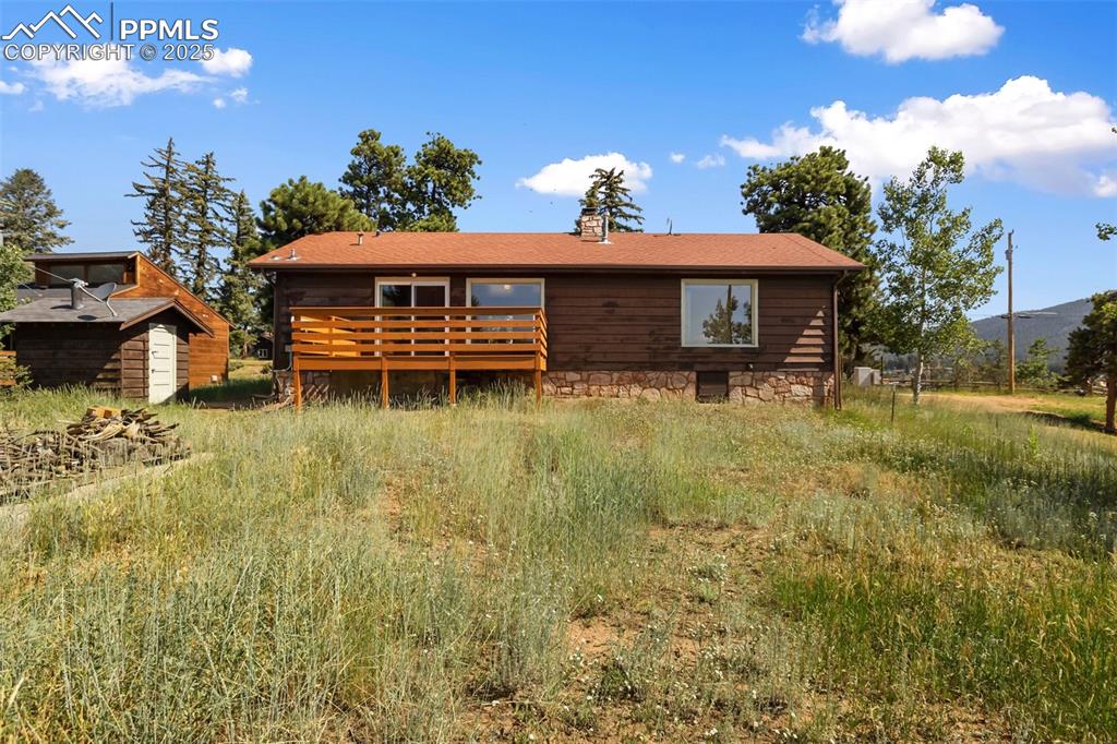 Image 34 of 35: Rear view of house with a deck, a chimney, and a storage unit