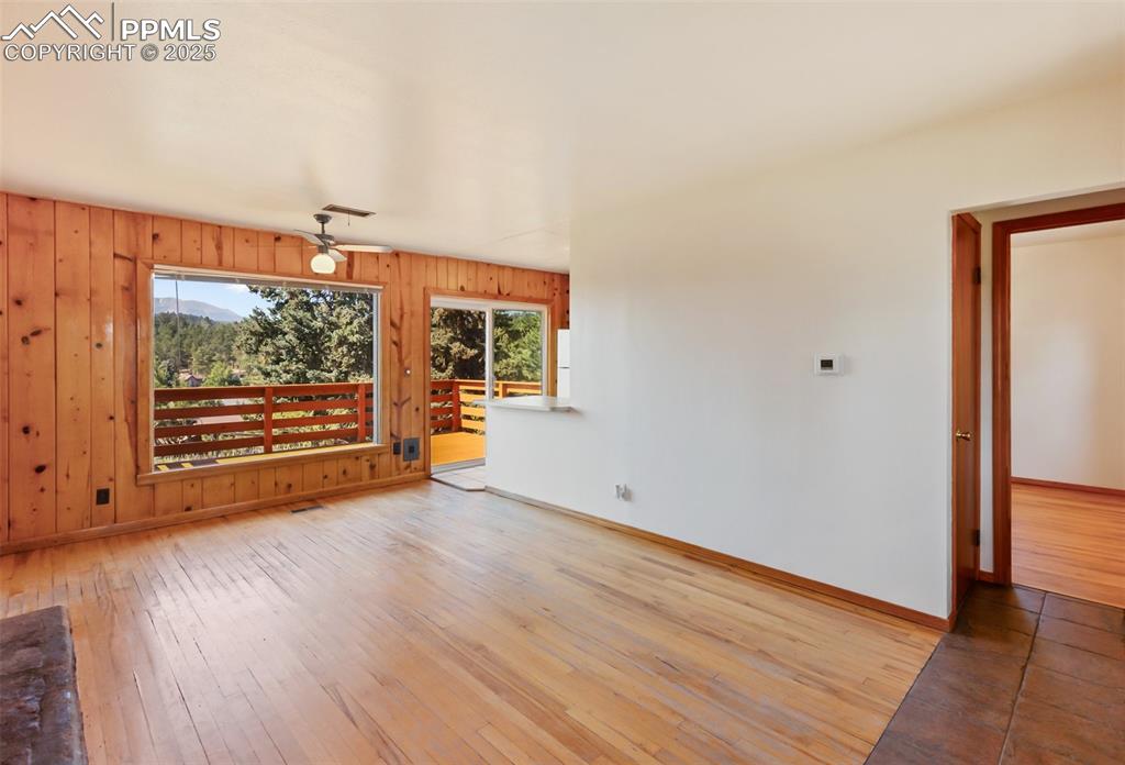 Image 9 of 35: Empty room featuring light wood-type flooring, a ceiling fan, and wood wall