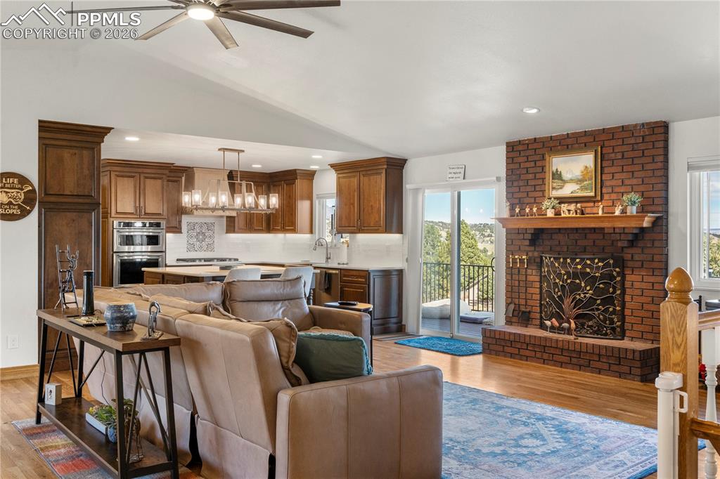Image 7 of 46: Living room with vaulted ceilings, hardwood flooring, wood burning fireplac