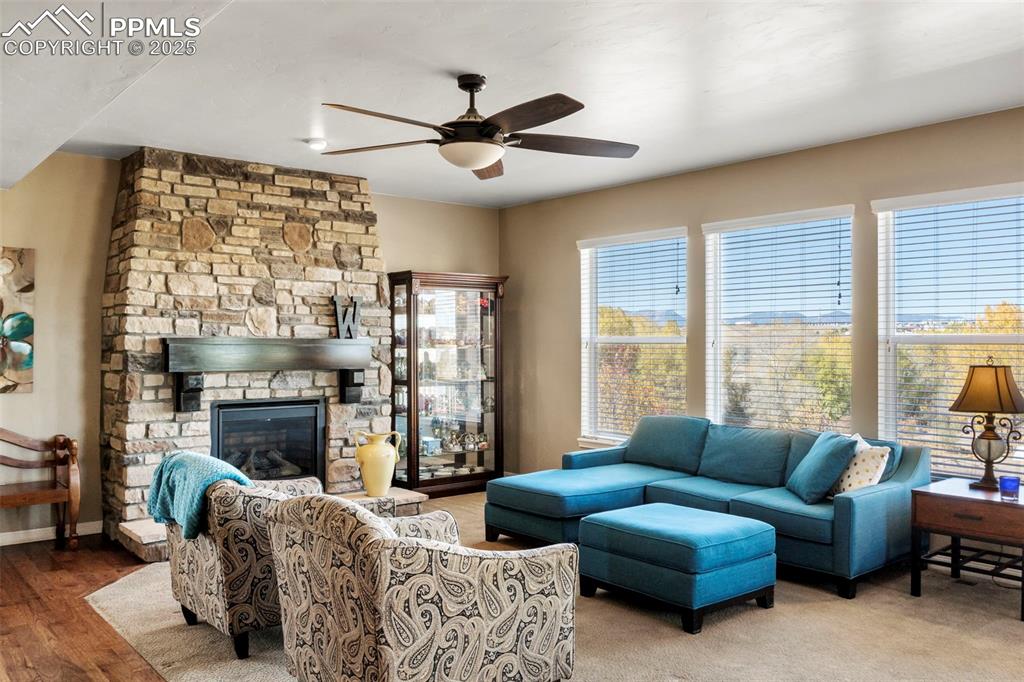 Image 12 of 41: Living room with a stone fireplace, ceiling fan