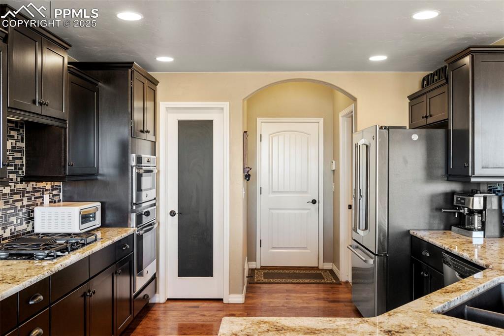 Image 15 of 41: Kitchen featuring light stone counters, tasteful backsplash, dark brown cab